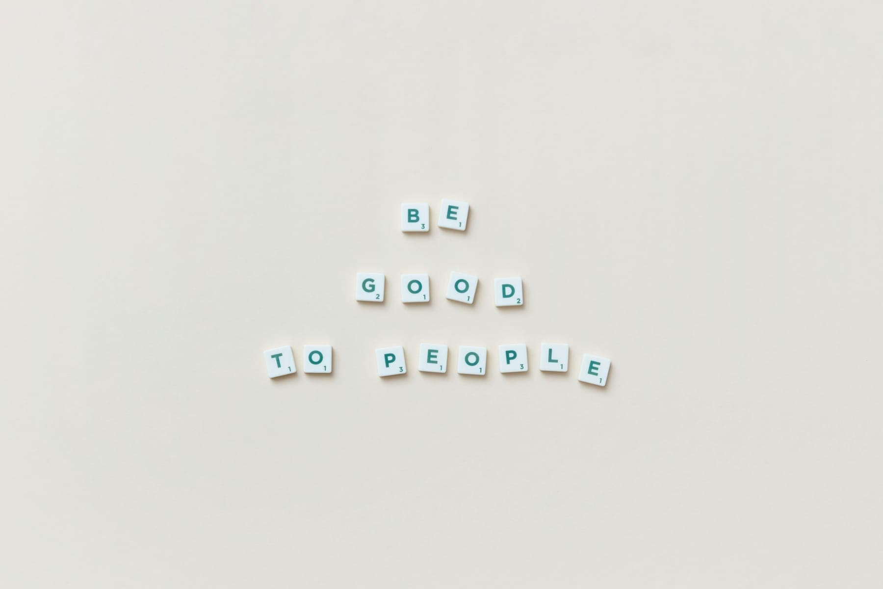 Scrabble tiles spelling Be Good To People on a cream background